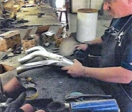 Craftsman buffing a stainless steel automotive engine exhaust part.