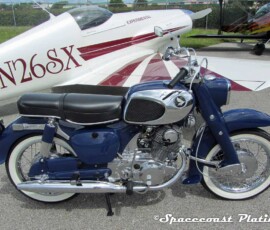 Classic early 1960s Honda CA77 Dream Touring restored and plated engine components, wheels, and trim. Experimental aircraft in the background.